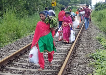 Residentes indios transportan sus pertenencias a lo largo de una vía de tren, el 19 de agosto de 2018, en Kerala.