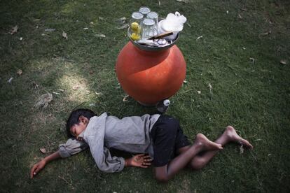 Un niño indio que se dedica a la venta de agua de limón descansa en la hierba de un parque público en una calurosa tarde de verano en Nueva Delhi, India. 6 de junio de 2014.