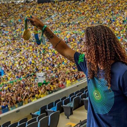 Rafaela Silva mostra sua medalha de ouro para os espectadores da partida entre a seleção feminina de futebol e Suécia.