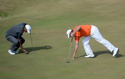 Tiger Woods coloca su bola y Westwood recoge la suya en el green del hoyo nueve.