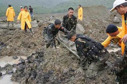 Soldados filipinos portan el cuerpo de una víctima rescatada del barro ayer en Guinsaugon.