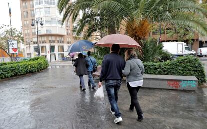 Varias personas pasean protegidas con paraguas este sábado por la mañana por el centro de Valencia, el 27 de octubre.