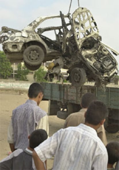 Jóvenes palestinos observan un coche alcanzado por misiles israelíes en Gaza.