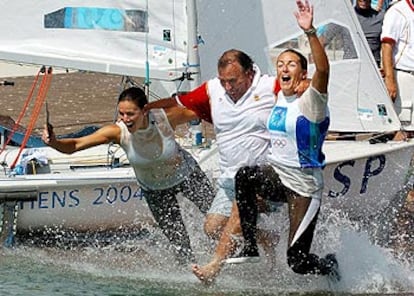 Natalia Vía-Dufresne (a la derecha) y Sandra Azón se lanzan al agua junto al director del equipo olímpico español, José María Benavides, tras conquistar la medalla de plata en la clase <i>470</i>.