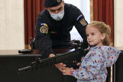 Una niña posa con un arma junto a un policía en el Parlamento de Rumania.