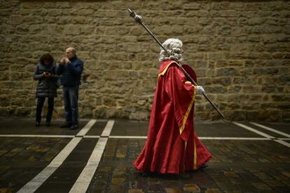 Un hombre vestido con un traje regional antiguo camina por una calle de Pamplona durante una procesión en honor a San Saturnino. ​