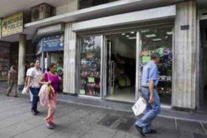 Varias personas caminan frente a un establecimiento comercial en Caracas (Venezuela).EFE/Archivo
