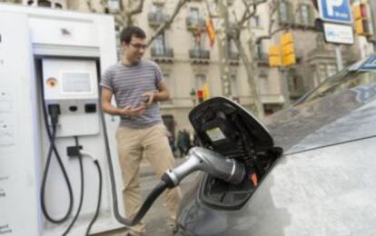 Un usuario de un veh&iacute;culo el&eacute;ctrico lo recarga en el paseo de Gr&agrave;cia de Barcelona.