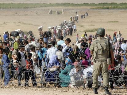 Kurdos sirios aguardan, frente a soldados turcos, en la valla fronteriza en Suruc, el 19 de septiembre