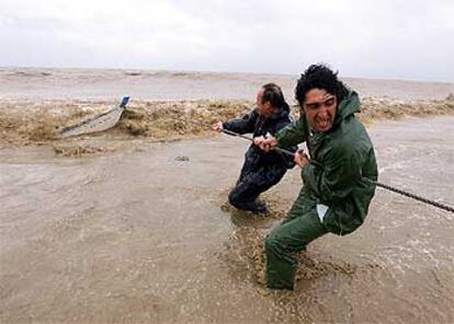 Dos pescadores intentan rescatar a su embarcación de la fuerza de la corriente, ayer en la playa de Rincón de la Victoria.