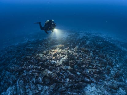 A diver examines the remains, which are covered by hundreds of amphorae.