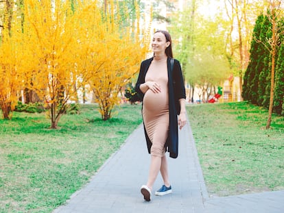 Una mujer embarazada camina por un parque.