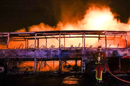 Los bomberos apagan un autobús durante los disturbios en Nanterre, esta madrugada. 