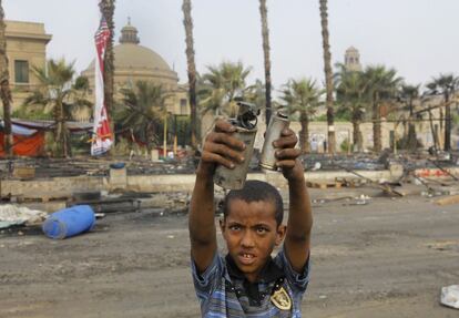 Un niño egipcio muestra dos granadas vacías de gas lacrimógeno entre los restos del campamento en la plaza Nahda, cerca de la Universidad de El Cairo en Giza. El Gobierno interino egipcio ha decretado el estado de emergencia en 11 provincias que se prolongará durante al menos un mes.
