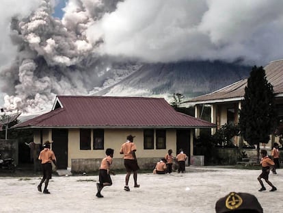 Alumnos juegan en el colegio con la erupción del monte Sinabung al fondo (Indonesia).