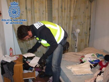 A police officer searches a home used by the prostitution ring.