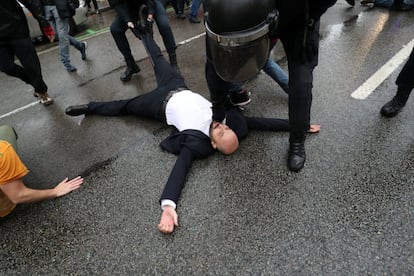 Um homem é imobilizado por um oficial da polícia em uma manifestação em frente a um centro de votação em Barcelona.