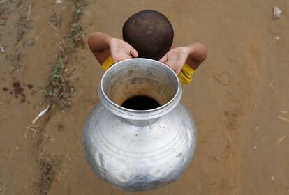 Un niño refugiado rohingya lleva un contenedor mientras camina con su padre para recoger agua en el campamento de refugiados de Palong Khali, cerca de Cox's Bazar (Bangladés).