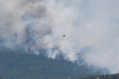 Un helicóptero intenta sofocar el incendio a las afueras de la ciudad de Lytton, arrasada por el fuego, el jueves. Los servicios meteorológicos de EE UU y Canadá han emitido decenas de avisos de récords de temperaturas en la zona. Pero el punto cero ha sido el municipio de Lytton (250 habitantes), en la Columbia Británica, donde se han registrado marcas históricas durante tres días consecutivos.