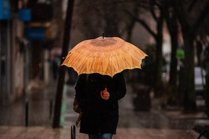 Una persona se protege de la lluvia con paraguas, en Madrid