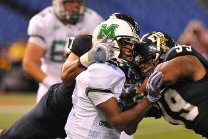 El defensa de fútbol americano Isame Faciane, con el número 99 en la camiseta negra de los International Panthers de Florida, bloquea al <i>quarterback</i> de los Marshall Thundering Herd, Rakeem Cato, en el estadio de Sant Petersburg,  Florida, en diciembre de 2011.