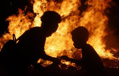 Dos personas frente a una hoguera, durante la noche de San Juan, en Terrassa (Barcelona).