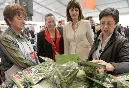 Una agricultora muestra sus productos en la feria bilbaína a la consejera de Agricultura, Pilar Unzalu; la portavoz del Ejecutivo, Idoia Mendia, y la directora de Turismo, Isabel Muela (de derecha a izquierda).