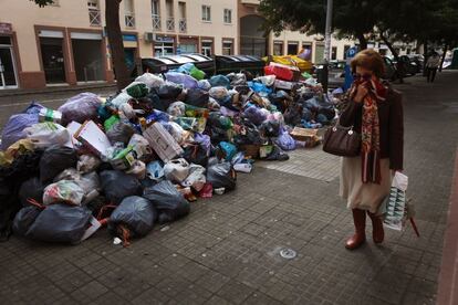 Una mujer se cubre la cara al pasar delante de basura sin recoger en una acera de Jerez de la Frontera.
