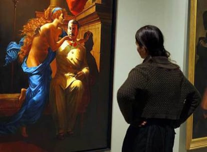 Una visitante observa el cuadro <i>Los orígenes del realismo socialista, </i>de la serie <i>Realismo socialista nostálgico 1982-1983,</i> de Vitaly Komar y Alexander Melamid; a la derecha, <i>La invención del arte del dibujo,</i> de Joseph Benoît Suvvèe, dos obras que se exponen en el Museo Thyssen de Madrid.