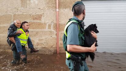 Dos agentes de la Guardia Civil trasladan a un vecino de Infesta y a un perro tras la riada.