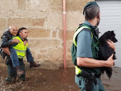 Dos agentes de la Guardia Civil trasladan a un vecino de Infesta y a un perro tras la riada.