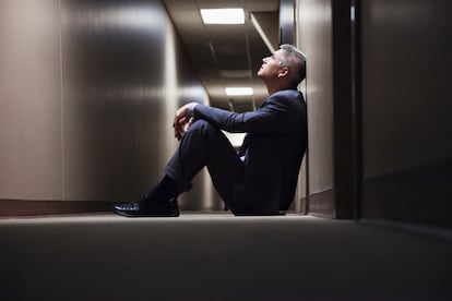 Caucasian businessman sitting on floor in corridor