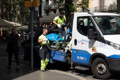 Operarios de la grúa municipal de Barcelona se llevan bicicletas de alquiler mal aparcadas, en septiembre.