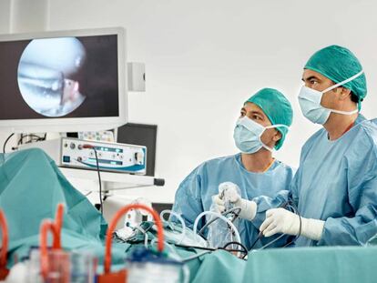 Cirujanos observan un monitor durante una intervención de rodilla.