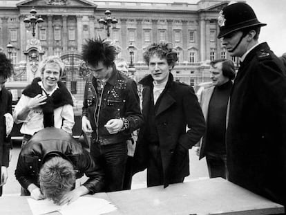 Así se las gastaban Sex Pistols. El grupo firma un contrato discográfico en la calle, a las puertas del Buckingham Palace en Londres. De izquierda a derecha, Johnny Rotten (voz), Steve Jones (guitarra, firmando), Paul Cook (batería), Syd Vicious (bajo) y el cerebro de todo, el mánager Malcolm McLaren. Un policía londinense vigila que la cosa no se salga de madre. Fue el uno de junio de 1977.