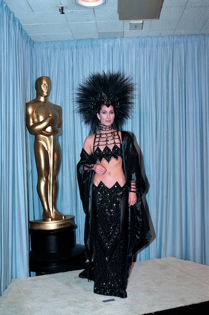 El vestido negro de Cher (1986). En los Oscar de 1986, Cher hizo historia con un vestido negro diseñado por su colaborador Bob Mackie. Con un ‘bralette’ de lentejuelas, una falda de tiro bajo, botas altas y un imponente tocado de plumas, su ‘look’ rompió las reglas del glamour tradicional. Cher defendió su elección: "No me importa si les gusta cómo me visto", dijo, anticipando quizá el eco cultural que tendría. Que le pregunten a Zendaya si no.