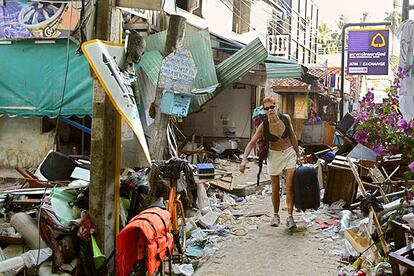 Una turista porta su equipaje por una calle devastada de la isla tailandesa de Phi Phi.