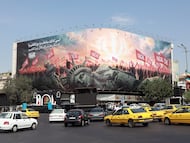 Vehículos pasan junto a una valla publicitaria antiestadounidense en la plaza Enghelab, en el centro de Teherán, Irán.