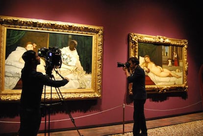 Un cámara y un fotógrafo francés delante de 'Olympia' de Manet y, a la derecha, 'La Venus de Urbino' de Tiziano.