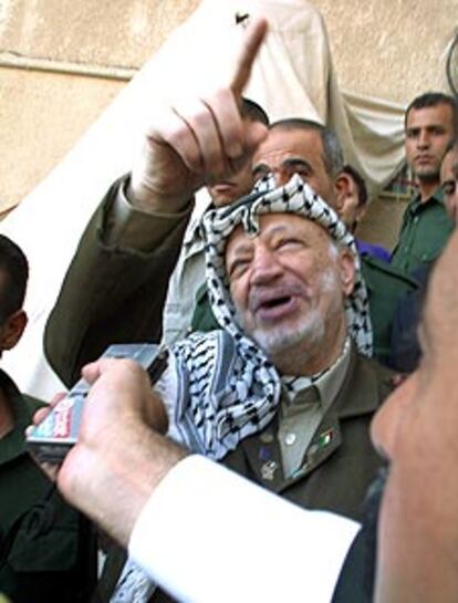 Arafat señala sobre su cabeza mientras sobrevuelan helicópteros israelíes.