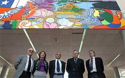 La pintora del mural Ximena Ahumada, y el embajador de Chile, Enrique Krauss, con el traje cruzado, junto a cargos universitarios.