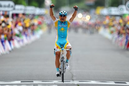 Vinokúrov celebra la victoria de etapa. Al fondo, el pelotón.