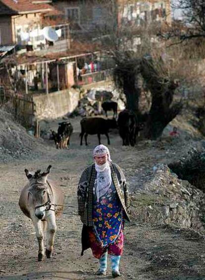 Una mujer musulmana camina con un burro en la aldea búlgara de Lazhnitsa.