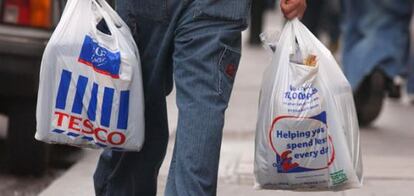 Un hombre lleva dos bolsas de plástico.