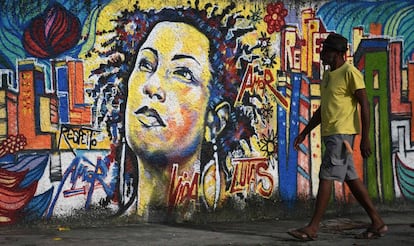 Homem caminha em frente a um mural de Marielle Franco, no Rio de Janeiro.