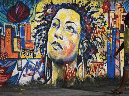 Homem caminha em frente a um mural de Marielle Franco, no Rio de Janeiro.