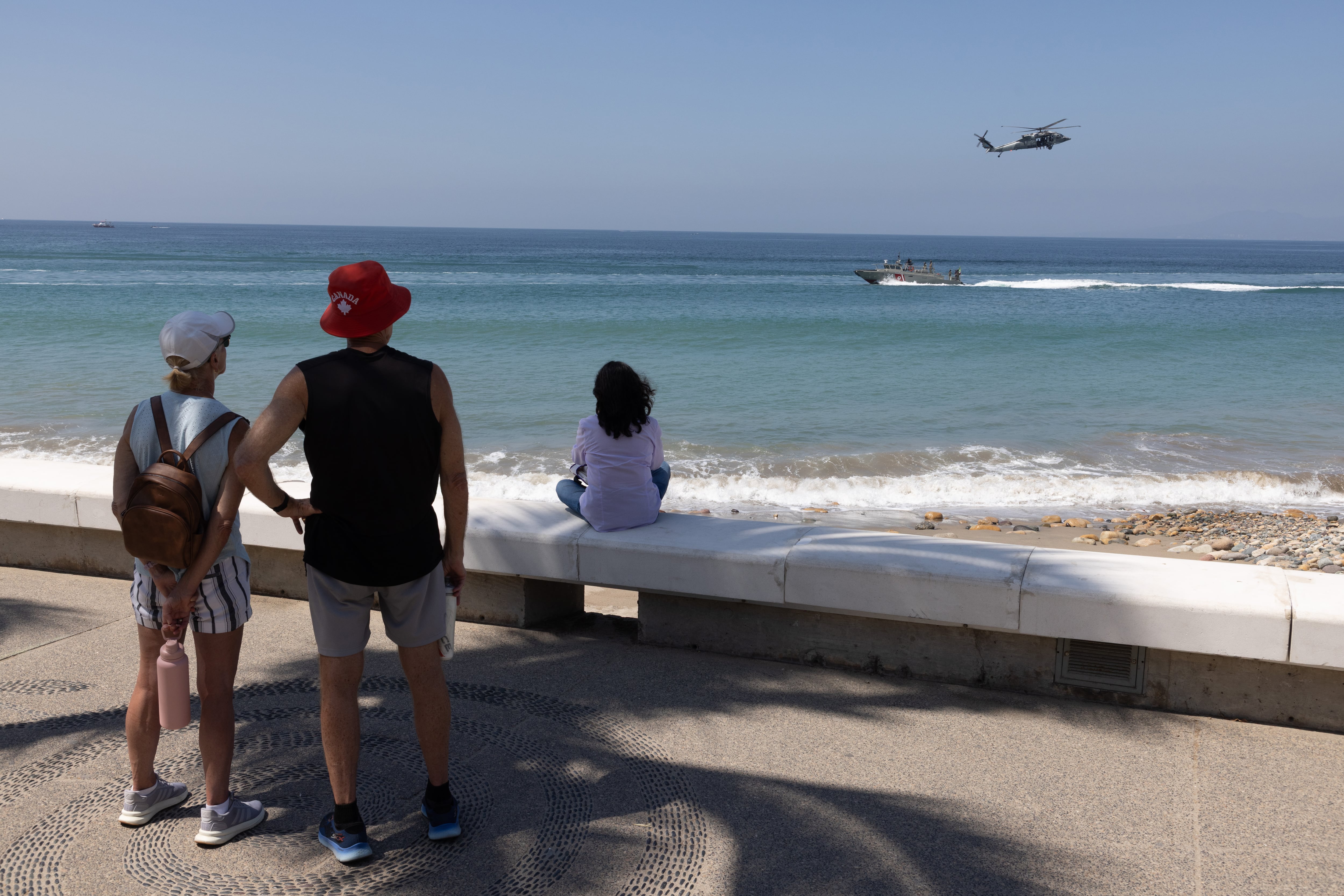 Turistas extranjeros observan unidades de la marina patrullando el malecón de Puerto Vallarta el 27 de febrero.