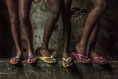 Três meninas exibem seus chinelos multicoloridos. Favela da Mangueira, Rio de Janeiro.