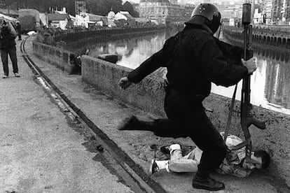 Bilbao, 26 de agosto de 1988. Un <i>beltza</i> ("negro"), miembro de la Brigada Móvil de la Ertzaintza (policía autonómica vasca), patea a un manifestante en la denominada <i>guerra de las banderas</i>, por la que se protesta en la Semana Grande frente al Ayuntamiento, cuando se iza la bandera española.