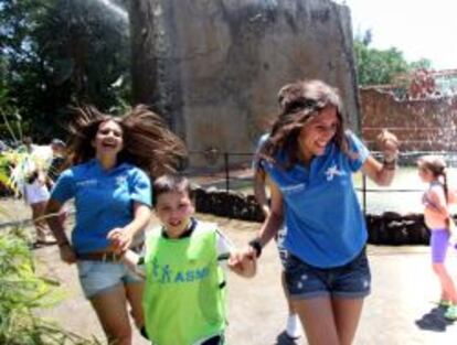 Voluntarias de La Caixa juegan con un niño en un parque temático.